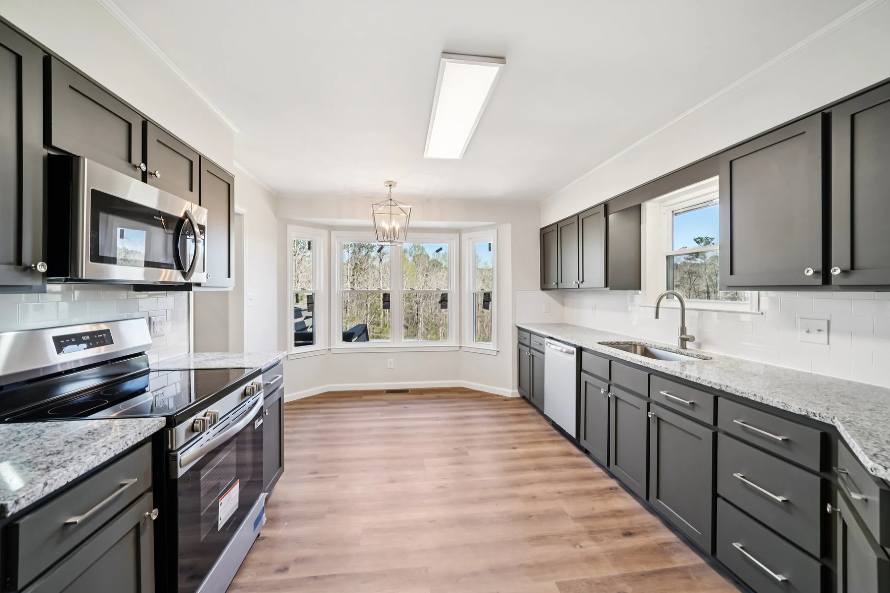 Remodeled kitchen with dark cabinetry, stone counters, and stainless appliances