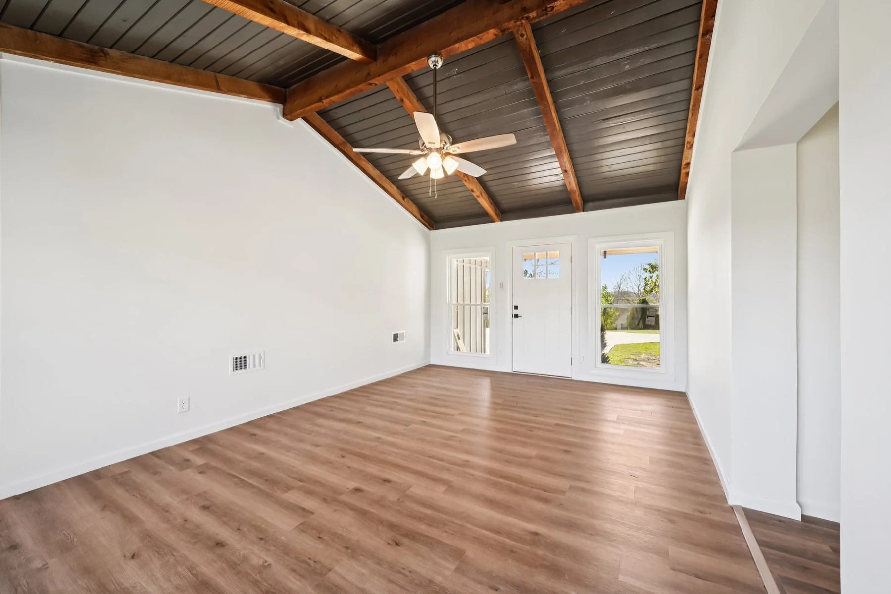 Renovated living room with warm wood floors and exposed ceiling beams